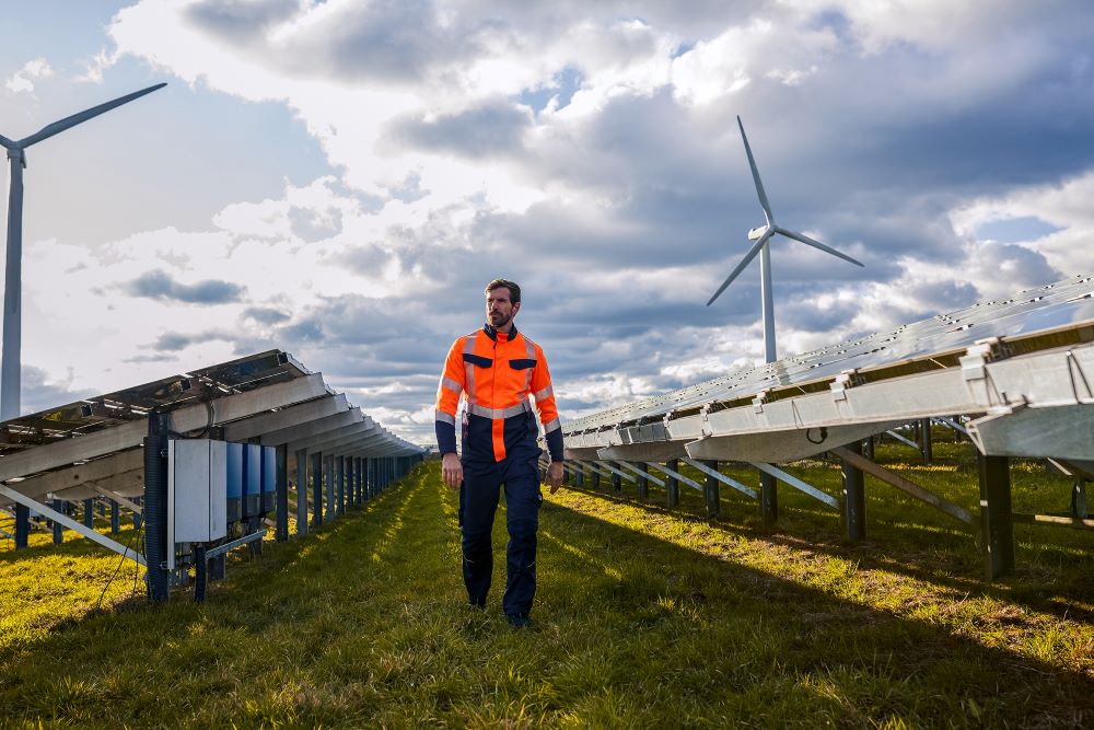A man walks through a solar installation wearing Multinorm high-visibility trousers.
